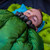is use shot of a  forest green shell lightweight down sleeping bag quilt with a charcoal gray interior being used to keep warm well sleeping