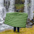 an in use shot of an opened up view of a person holding a forest green lightweight down blanket style sleeping bag quilt in front of a waterfall