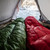 an in use shot of a person utilizing their forest green and red shell lightweight down sleeping bags in cold temperatures